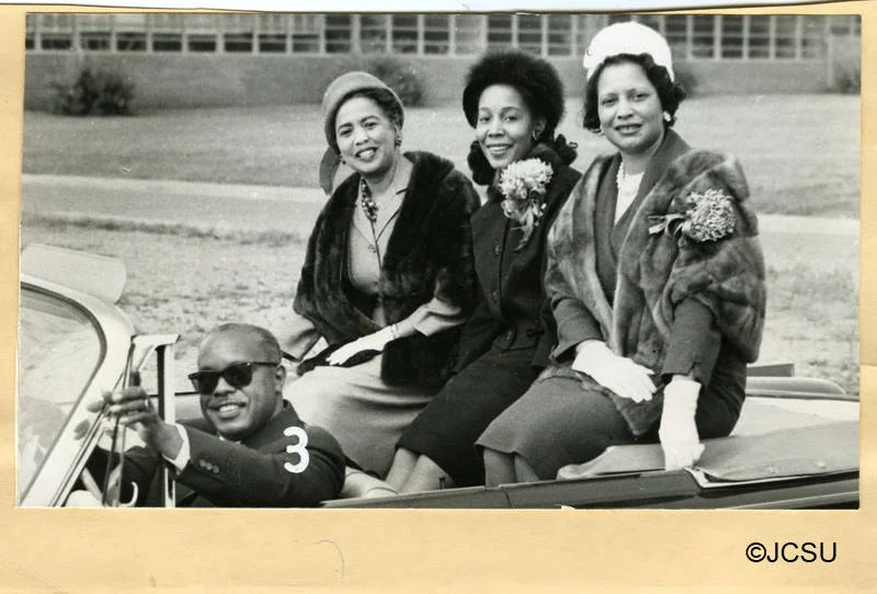 A parade float carrying three former Homecoming Queens